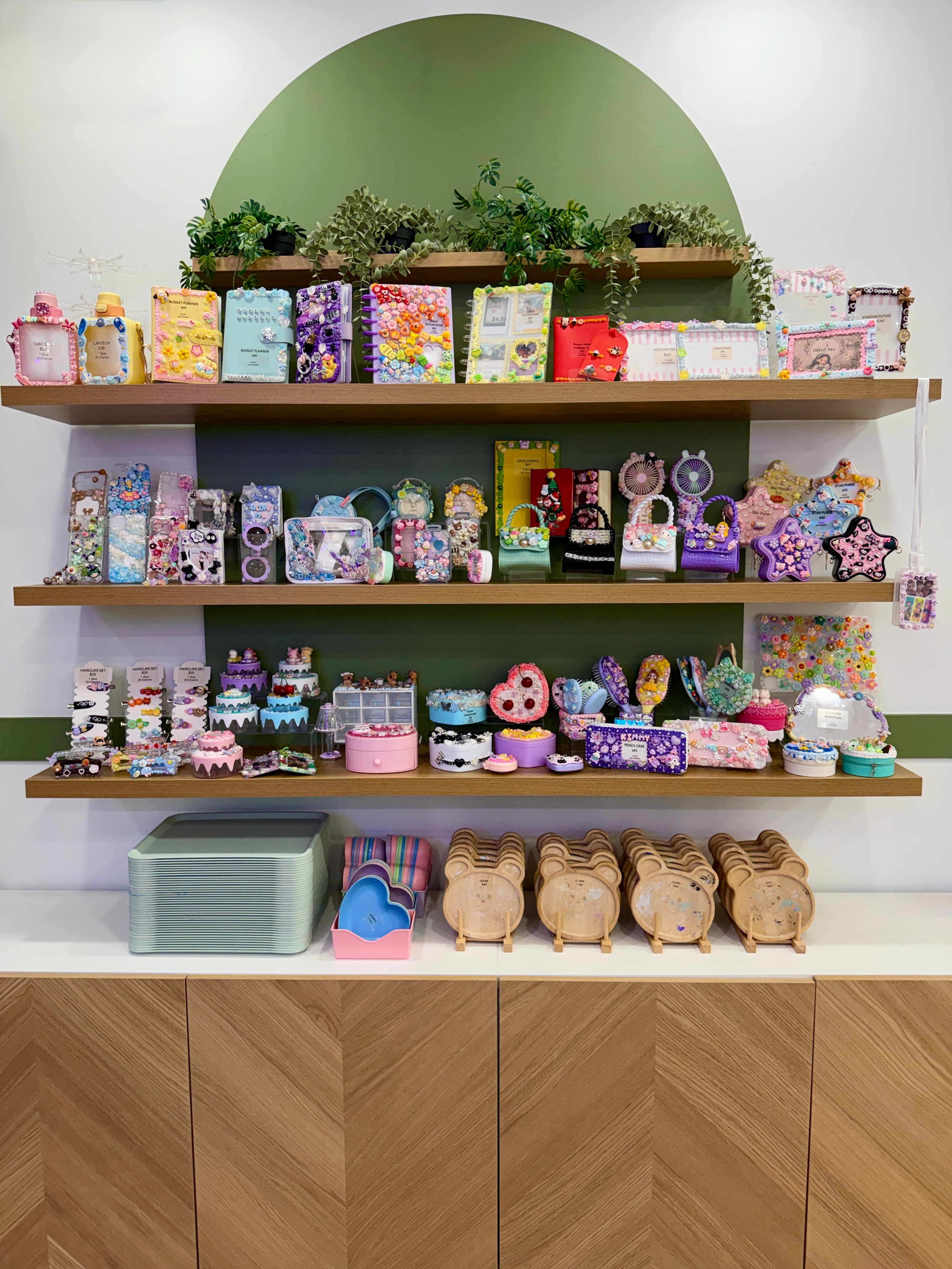 Colorful Decoden decorated items displayed on shelves at Olive Me Studio